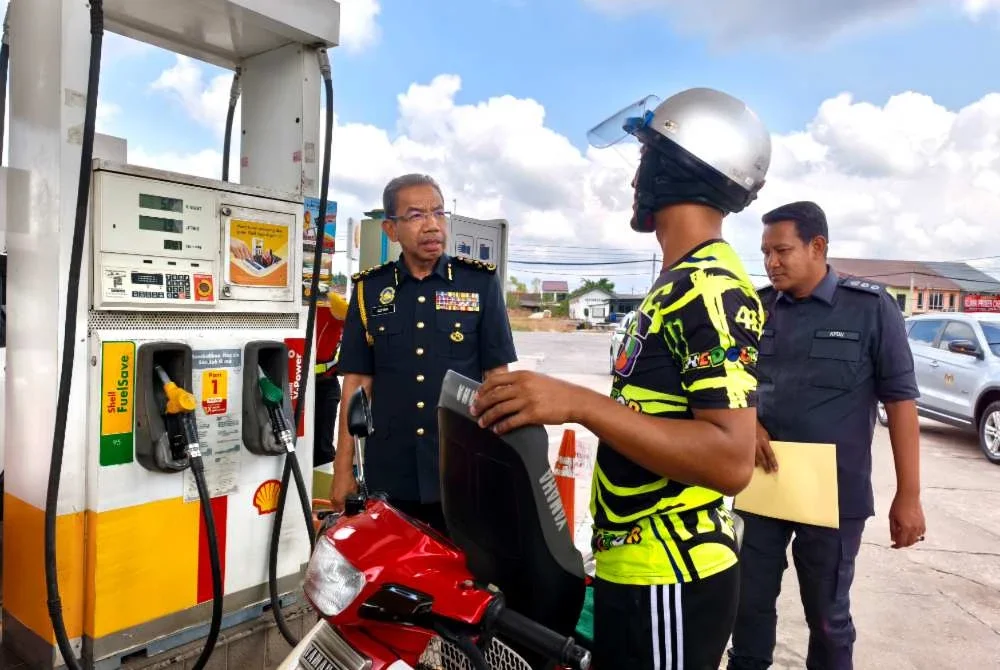 Azman (kiri) melihat seorang pengguna menikmati kemudahan BUDI95 semasa sesi lawatan kerja beliau di sebuah stesen minyak di Rantau Panjang pada Ahad.Foto Sinar Harian/Hazelen Liana Kamarudin