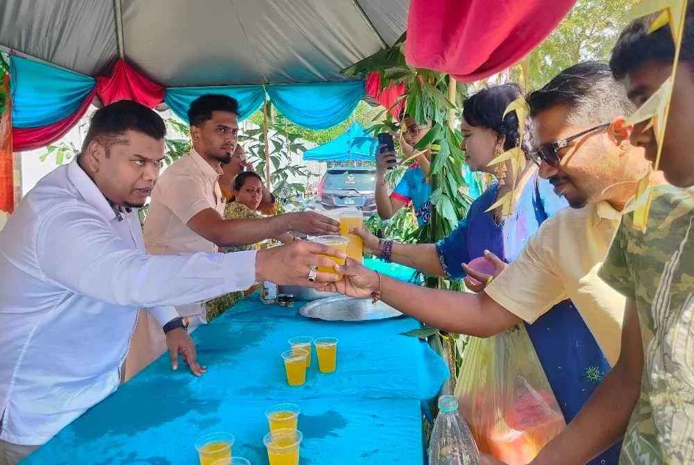 Muhamad Arafat (kiri) bersama Sharvin (kanan) membantu mengedarkan air minuman percuma kepada orang ramai ketika program pemberian air percuma sempena Hari Thaipusam di Tanjung Rambutan pada Ahad.