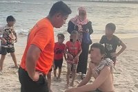 Anggota penyelamat pantai APM bersama dua beranak yang diselamatkan selepas hampir lemas ketika mandi di Pantai Cerating pada Sabtu.