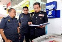 Azman (kanan) memeriksa buku di salah sebuah stesen minyak di Rantau Panjang semasa sesi lawatan kerja beliau pada Ahad