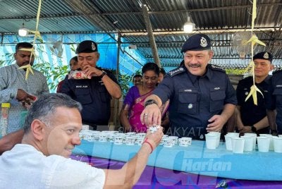 Azizee (tengah) memberi air minuman kepada penganut Hindu yang singgah di panthel PDRM di Jalan Kebun Bunga pada Ahad.