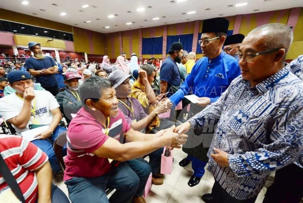 Ibrahim (kanan) bersalaman dengan salah seorang penerima zakat pada majlis tersebut.