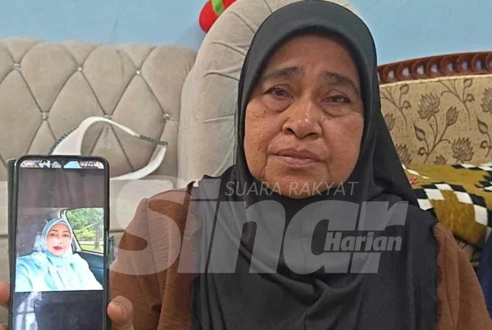 Norsiah menunjukkan gambar Allahyarham Zahrullail dalam telefon bimbitnya.