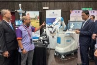 Abdul Rahman (kanan) mendengar penerangan daripada Amran (dua dari kiri) tentang robot ROSA.