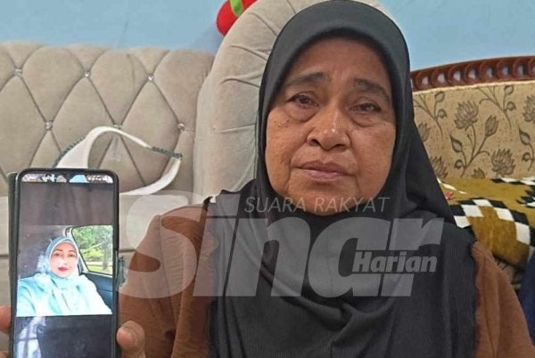 Norsiah menunjukkan gambar Allahyarham Zahrullail dalam telefon bimbitnya.