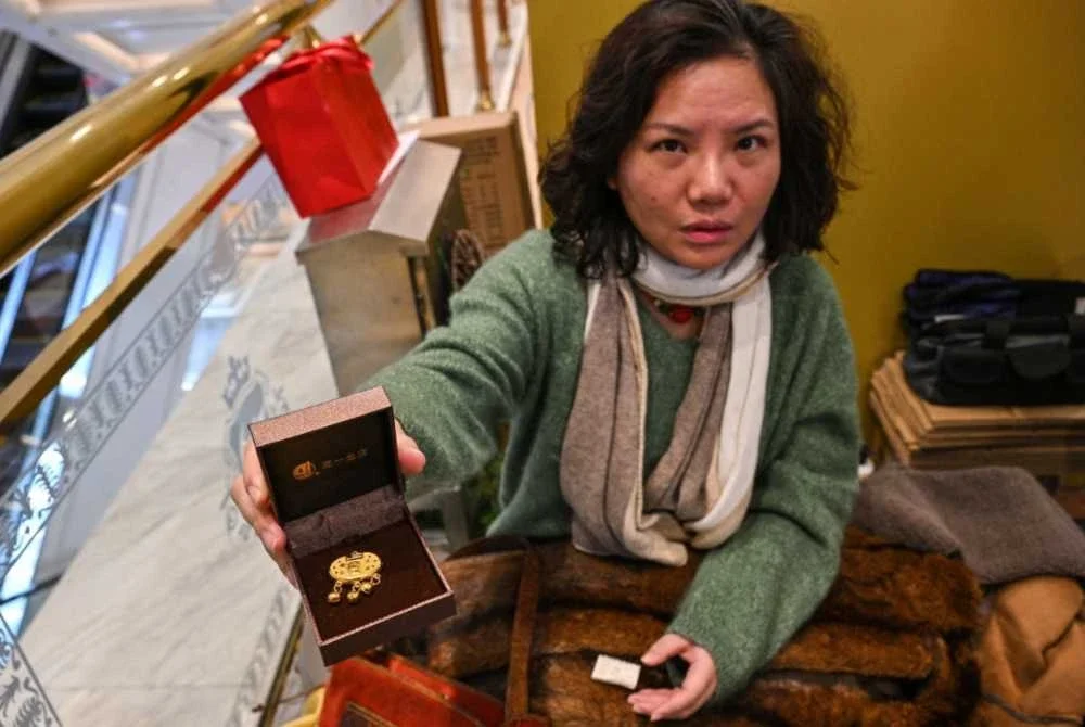 Seorang wanita menunjukkan barang kemas untuk dijual pada mesin tersebut. Foto: AFP