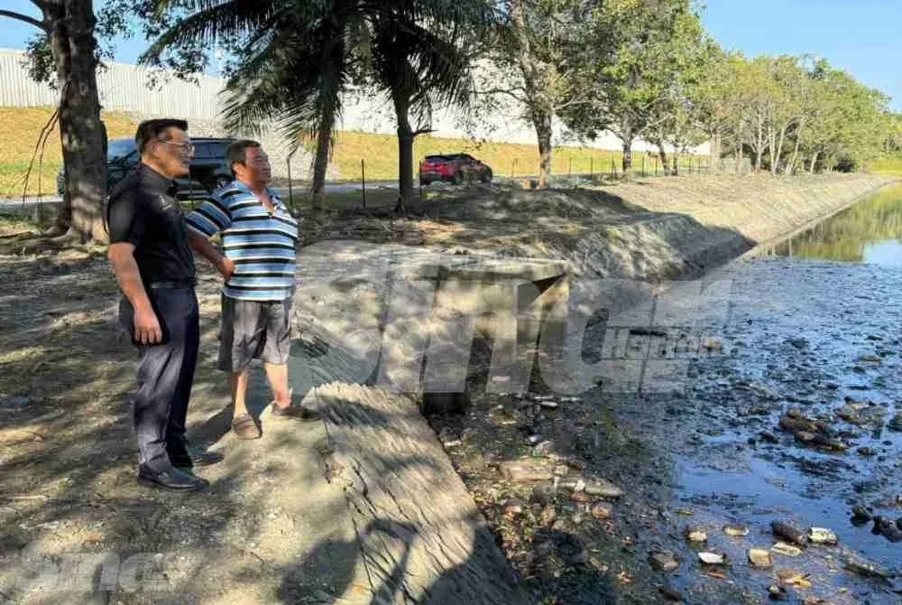 Ban Hong (kiri) menjnjau keadaan kolam takungan banjir di kawasan industri Bukit Rambai pada Selasa.