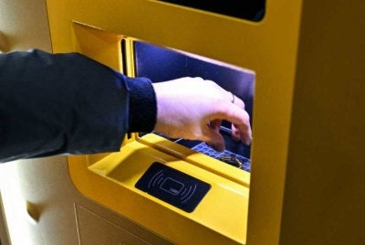 Seorang petugas memasukkan barang kemas ke dalam mesin kitar semula. Foto: AFP