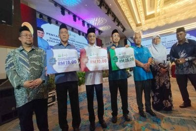 Mohamad (tiga dari kiri) bersama pegawai kanan Zakat MAINPP menunjukkan kadar zakat fitrah bagi tahun 2026 untuk Pulau Pinang.