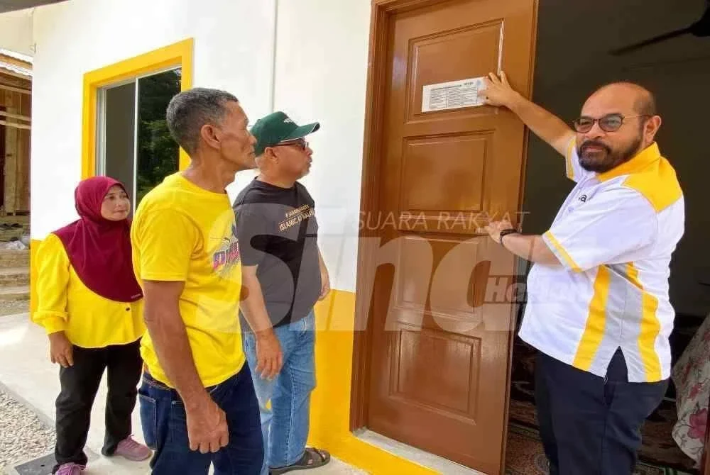 Zafri (kanan) bersama Zawahir (tiga,kiri) menampal tanda penyerahan rumah kepada Razak (kiri) dan isteri di RPT Chucoh Puteri B, Kuala Krai. Foto: SINAR HARIAN/HAZELEN LIANA KAMARUDIN
