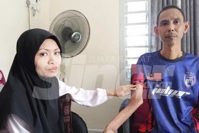 Jamaliah menunjukan lengan suaminya,Mohamed Hafiz selepas pembedahan membuang ketulan dilakukan.