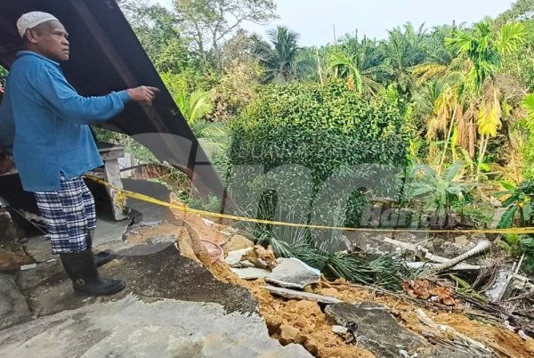 Abdul Hamid menunjukkan keadaan cerun runtuh menjejaskan empat rumah termasuk rumahnya di Kota Perdana, Pekan.