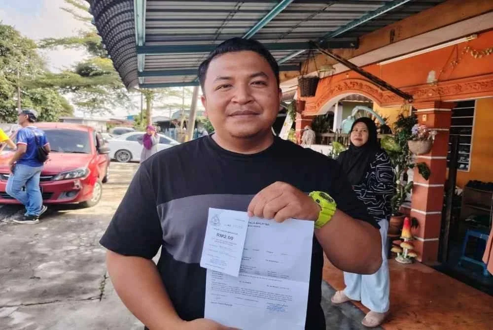 Muhamad Nur Hatim menunjukkan laporan polis apabila rumahnya dilanda puting beliung di Taman Damai pada petang Rabu.