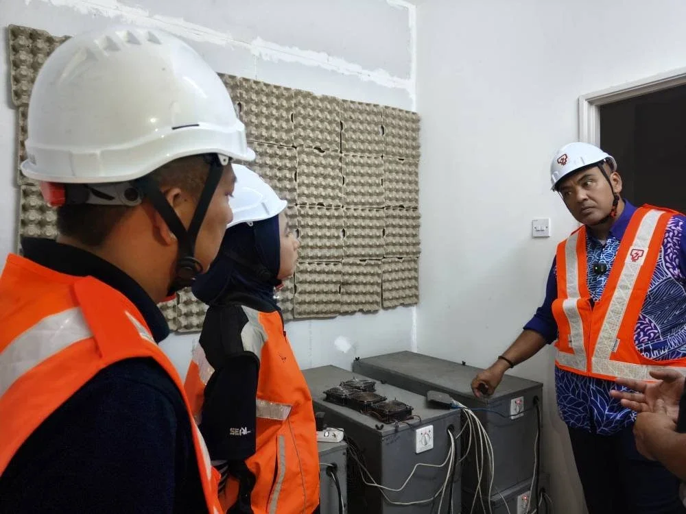 Mohd Noor Helmy (kanan) melihat mesin bitcoin yang terdapat pada rumah kosong berkenaan.