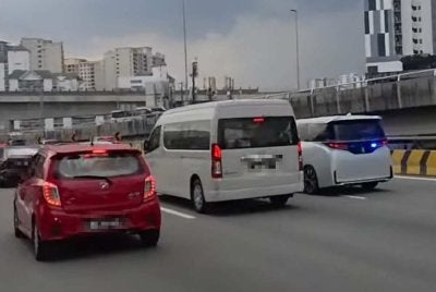 Polis sedang menyiasat sebuah kenderaan (kanan) memasang lampu berkelip biru berserta siren di Lebuhraya MEX pada Rabu.