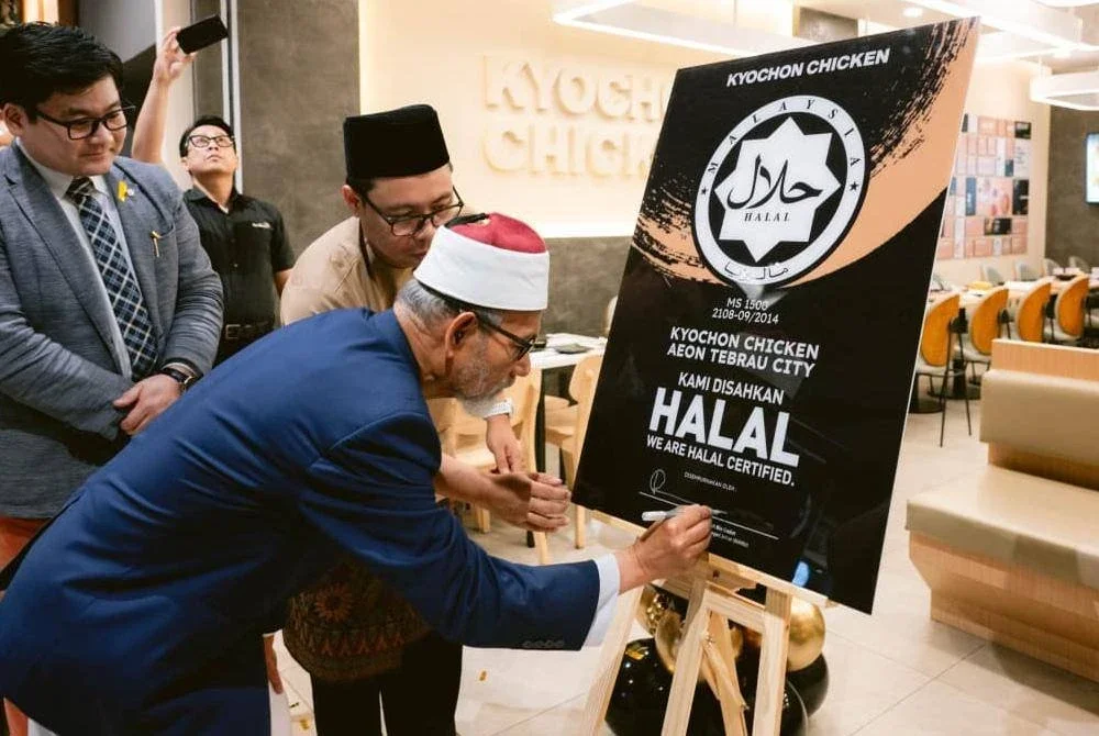 DATUK DR NOOH menurunkan tandatangan merasmikan restoran Kyochon yang mendapat sijil halal di Aeon Mall Tebrau City, Johor Bahru baru-baru ini. 