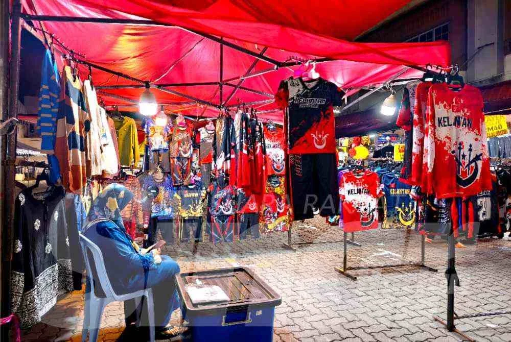 Wan Nur Hafizah hanya mampu bermain telefon apabila tiada pelanggan yang datang ke gerainya di Pasar Borong Wakaf Che Yeh, Kota Bharu. - Foto:SINAR HARIAN/HAZELEN LIANA KAMARUDIN