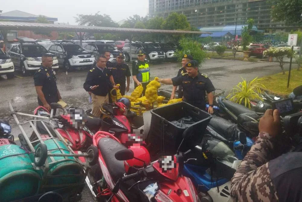 Muhammad Kifli (kanan) melihat motosikal yang disita.