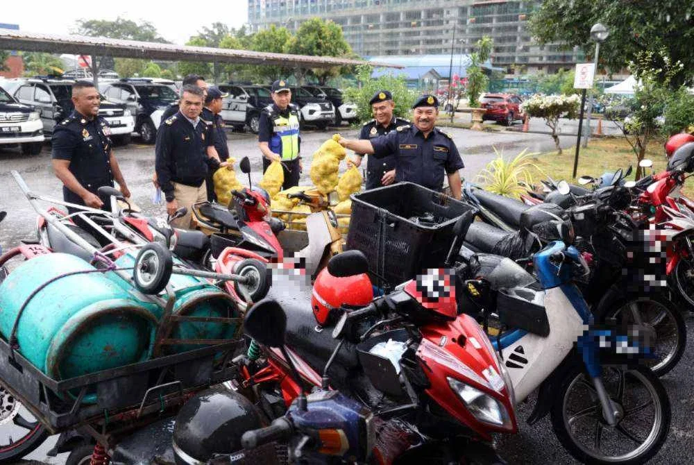 Muhammad Kifli (kanan) melihat motosikal yang disita.