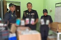 Ketua Pegawai Penguatkuasa KPDN Perak, Mohamad Kamarol Mat Nor (tengah) menunjukkan sebahagian 529 telefon bimbit tiruan menggunakan jenama terkenal dari China yang disita dalam serbuan pada Khamis.