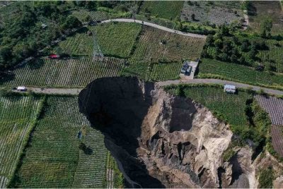 Pemandangan dari udara menunjukkan pekerja syarikat elektrik negara PLN menghentikan operasi menara penghantaran voltan tinggi berhampiran kejadian tanah runtuh di Kampung Pondok Balik, Kecamatan Ketol, Aceh. Foto AFP
