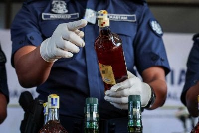 Rohaizad menunjukkan minuman keras tiruan yang dirampas dalam satu operasi di Sungai Dua, Pulau Pinang. Foto Bernama