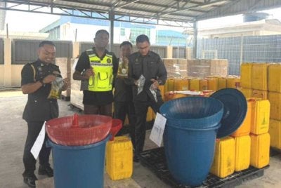 Jegan (dua dari kiri) menunjukkan minyak masak bersubsidi yang dirampas dalam serbuan di sebuah stor haram di Tasek Gelugor, malam Khamis. Foto KPDN Pulau Pinang