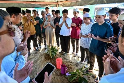 Muhammad Aizat Hairi (dua dari kanan) mengaminkan doa ke atas jenazah bapanya, Allahyarham Zulharisam Awang yang juga legenda bola sepak Terengganu di Tanah Perkuburan Islam Mok Suri, Pekan Batu 6 hari ini. - Foto: Bernama
