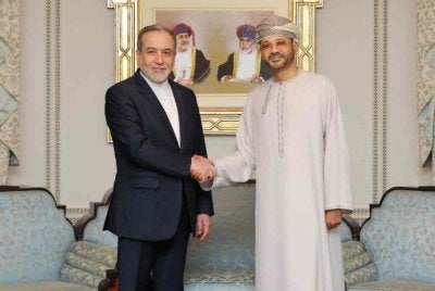 Araghchi (kiri) bersalaman dengan al-Busaidi ketika bertemu di Muscat.