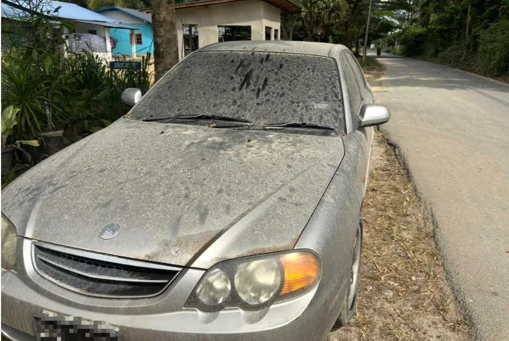 Kereta penduduk yang dipenuhi debu tanah daripada muatan lori. 