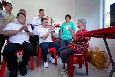 Kor Ming (dua, kiri) beramah mesra bersama pemilik rumah, Chan Fook Yan, 71, (kanan) ketika hadir pada perasmian bina baru rumah sempena program Sentuhan Kasih KPKT di Kampung Baru Simpang Jalong. Foto Bernama