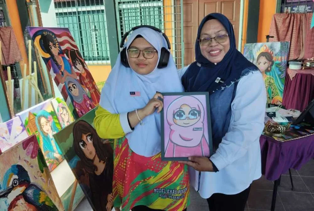 Jamkhuriyati (kanan) menunjukkan karikaturnya yang dilukis oleh Ainul Syeefa.