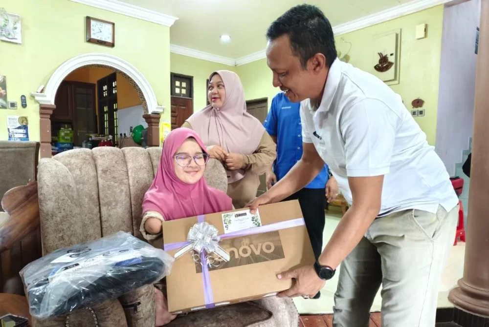 Rozi (kanan) menyerahkan sumbangan kepada Nur Damia Irsalina ketika kunjungan ke rumah gadis itu di Kampung Lubuk Batu, Hulu Terengganu pada Ahad.
