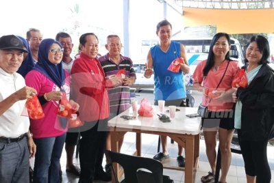 Ahmad (tiga dari kiri) mengedarkan buah limau kepada penduduk sekitar Pasar Awam Benut pada Ahad.