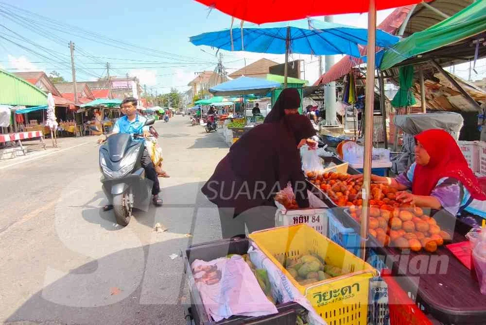 Kamariah (kanan) sedang melayan pelanggan di gerai buahnya di Tak Bai, Narathiwat. Foto:SINAR HARIAN/HAZELEN LIANA KAMARUDIN