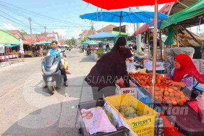 Kamariah (kanan) sedang melayan pelanggan di gerai buahnya di Tak Bai, Narathiwat. Foto:SINAR HARIAN/HAZELEN LIANA KAMARUDIN