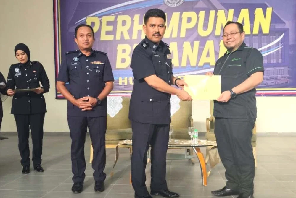 Mohd Rusyhidi (kanan) menerima surat penghargaan daripada PDRM yang diserahkan oleh Superintenden Sharudin Abdul Wahab pada Majlis Perhimpunan Bulanan IPD Hulu Terengganu pada Selasa.