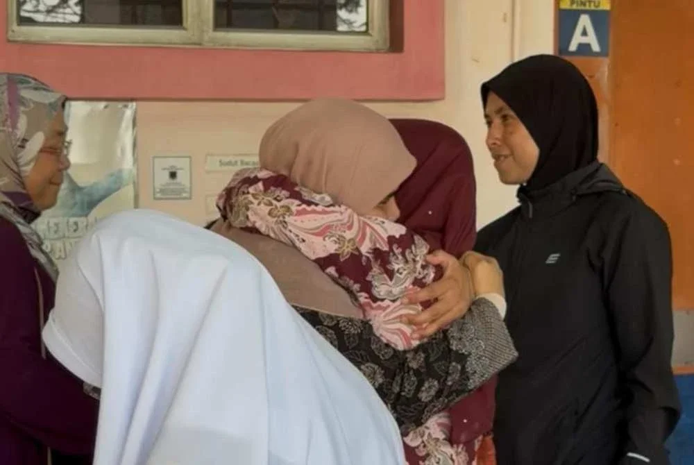 Isteri arwah ditenangkan kenalan dan ahli keluarga di pekarangan Jabatan Forensik Hospital Melaka pada Selasa.