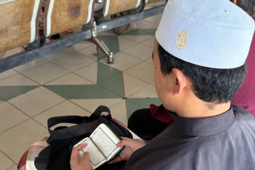 Anak arwah membaca yassin sementara menunggu proses menuntut jenazah di Hospital Melaka pada Selasa.