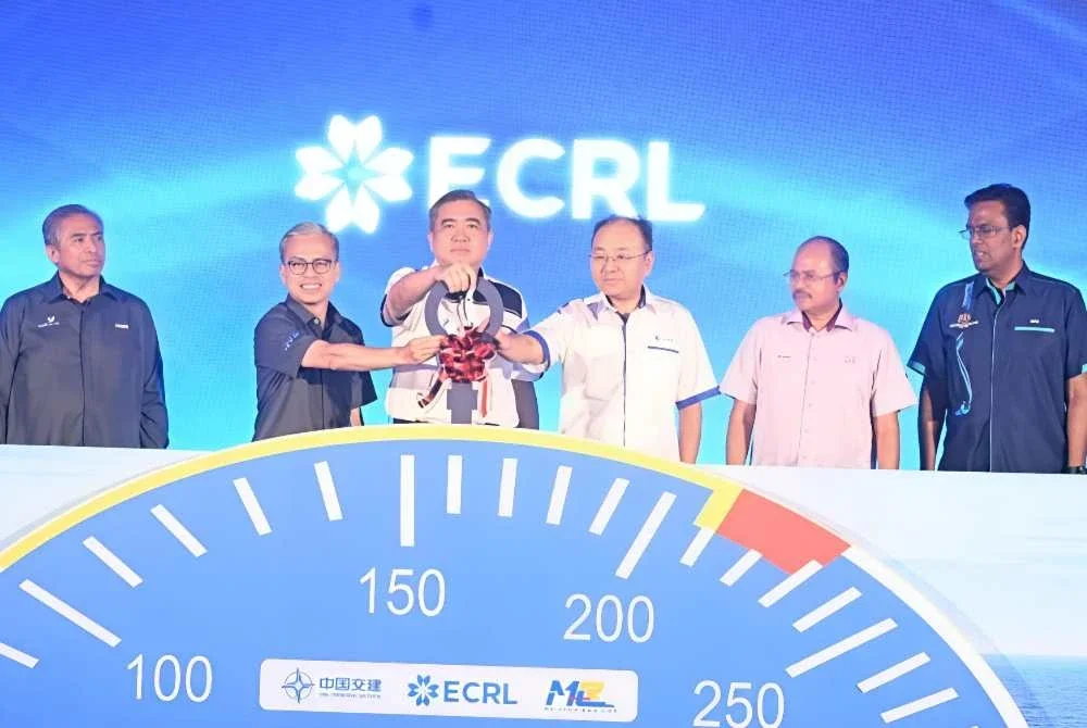 Fahmi (dua dari kiri) mengiringi Anthony Loke menyempurnakan gimik pelancaran Golden Tren EMU dan E-Loco di Stesen ECRL KotaSAS pada Rabu.