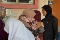 Isteri arwah ditenangkan kenalan dan ahli keluarga di pekarangan Jabatan Forensik Hospital Melaka pada Selasa.