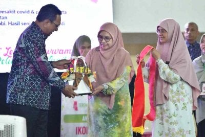Mohd Azmi menyampaikan anugerah Inspirasi Wanita kepada Tuan Faizah sempena Sambutan Terengganu Hijab Day di Kompleks Sukan Negeri Terengganu, Gong Badak di Kuala Nerus pada Khamis.