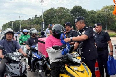 Dzulkhairi menyampaikan kit kepada pengguna jalan raya sempena pelancaran Ops Selamat Tahun Baharu Cina pada Khamis.