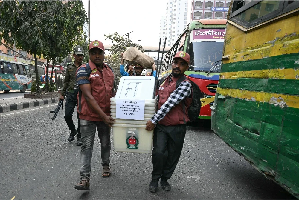 Pegawai pilihan raya mengangkut peti undi ke pusat pengundian di Dhaka. - AFP