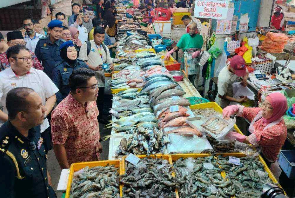 Kah Leong (dua dari kiri) ketika meninjau jualan ikan sempena Majlis Peluncuran dan Sesi Walkabout Skim Harga Maksimum Musim Perayaan Tahun Baharu Cina 2026 di Pasar Besar Ipoh di sini pada Jumaat.
