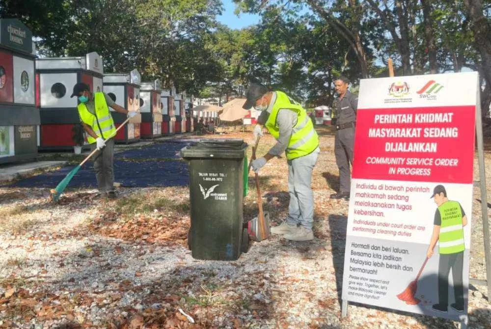 Anggota penguatkuasa SWCorp memantau dua lelaki yang mengaku bersalah membuang sampah di tempat awam melaksanakan PKM di kawasan Stadium Darul Aman pada Jumaat.