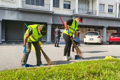 Mohd Hashim dan Herrykurniawan menyapu sampah di kawasan Nilai sebagai denda bagi kesalahan membuang puntung rokok merata-rata.