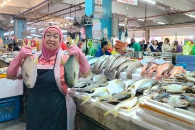 Roshni menunjukkan ikan bawal emas yang dijual di gerainya di Pasar Besar Ipoh di sini pada Jumaat.