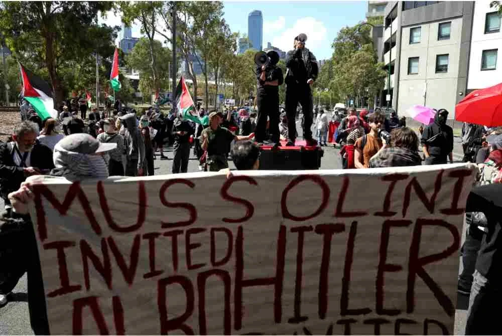 Dua penunjuk perasaan berdiri di atas tong sampah sambil berucap menggunakan pembesar suara di hadapan anggota polis yang mengawal keadaan.