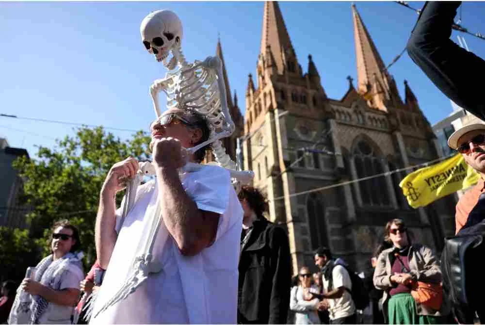 Seorang penunjuk perasaan membawa rangka plastik manusia di bahunya di sebagai simbolik jenayah yang dilakukan Presiden Israel.